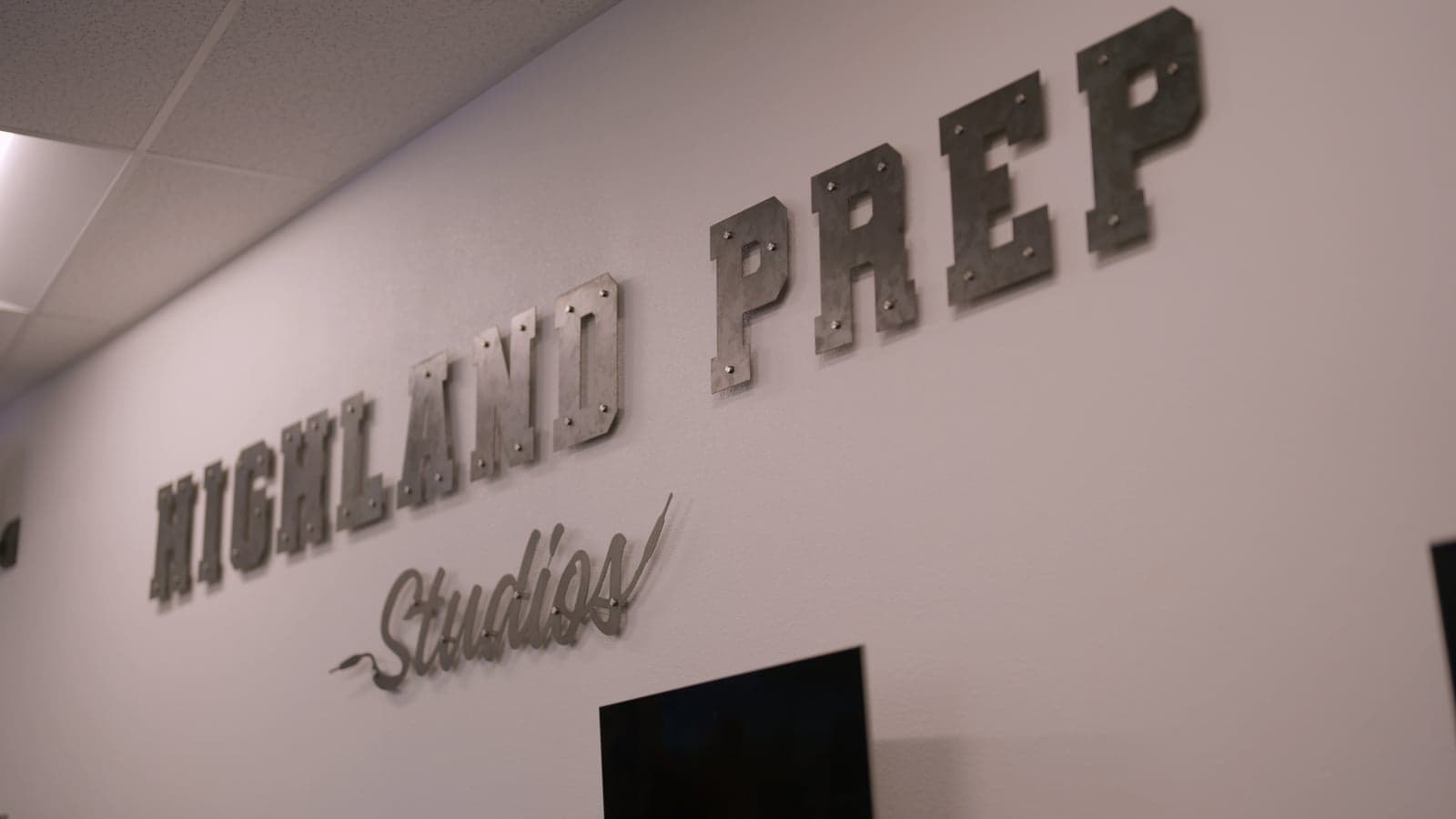 A metal Highland Prep Studios sign fabricated by students, mounted on a wall